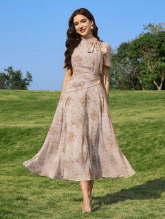 Mujer posando en un campo verde con un vestido midi floral de color beige y lazo al cuello.
