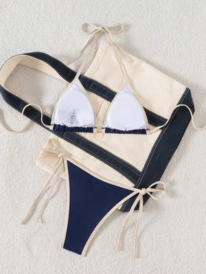 Primer plano del top de bikini triangular azul marino con tirantes y borde en color crema.