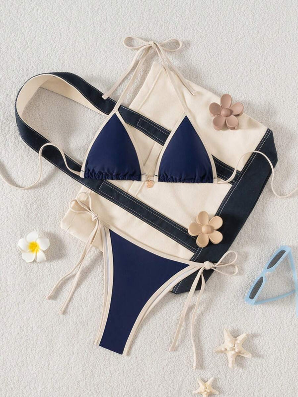 Detalle de la parte inferior de un bikini azul marino con lazos laterales y ribete a contraste.
