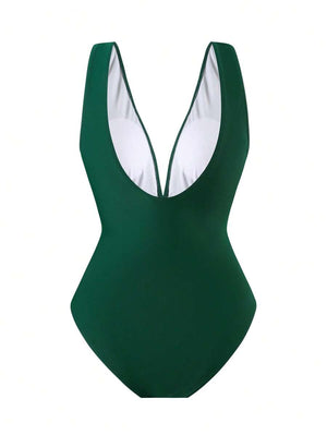 Detalle del adorno dorado en forma de concha en la cintura del traje de baño verde, uniendo la parte superior e inferior.