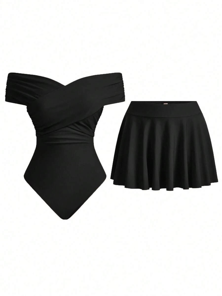 Conjunto de traje de baño negro de dos piezas con bañador de hombros descubiertos y falda corta acampanada, sobre fondo blanco.