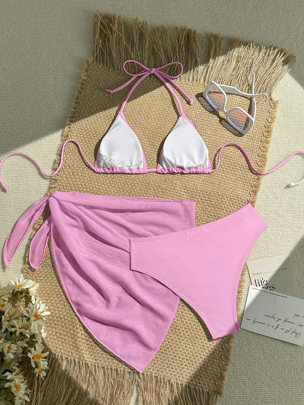 Imagen 1: Vista superior del Conjunto De Bikini Rosa de 3 piezas sobre una alfombra de mimbre.