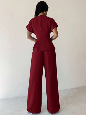 Primer plano de la blusa peplum color burdeos con mangas murciélago y cuello redondo del conjunto elegante.