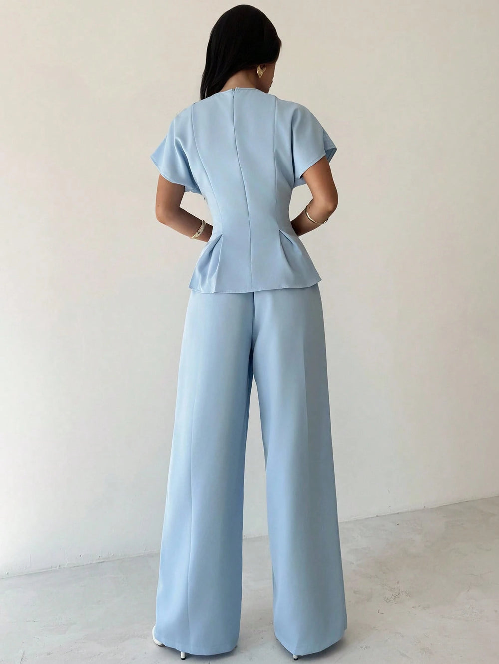 Conjunto azul elegante con blusa asimétrica y pantalón largo.