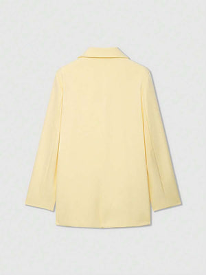 Detalle del cuello y la solapa de un blazer amarillo claro sobre fondo blanco.