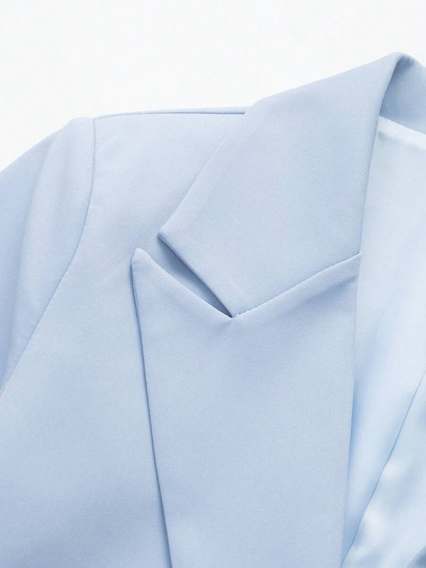 Primer plano de los botones negros y bolsillos de un blazer celeste.