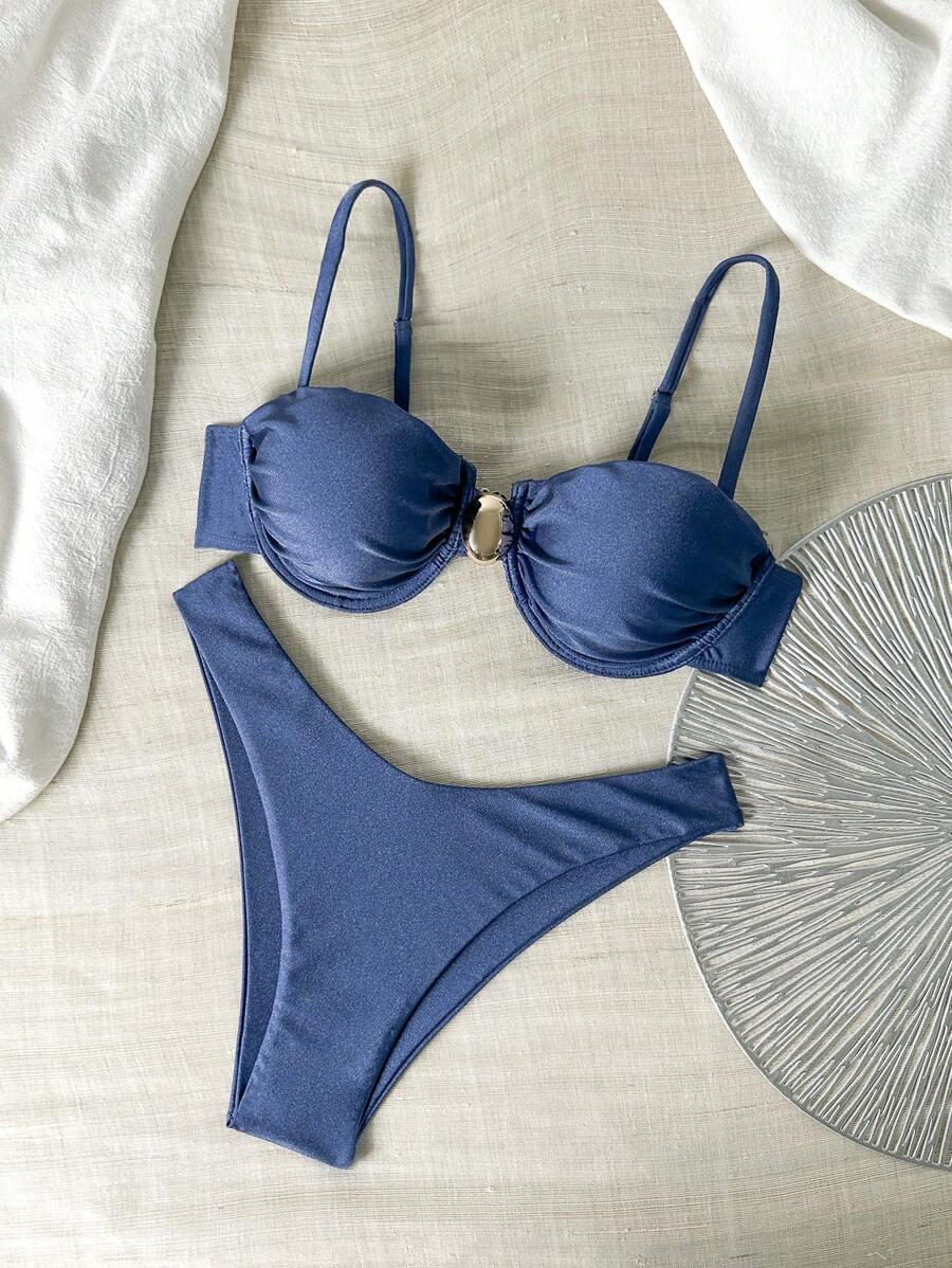 Bikini azul marino con top fruncido y aro dorado en V, y braguita cheeky de corte alto.