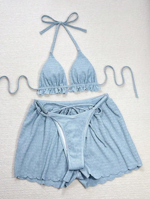 Mujer de perfil usando un conjunto de verano azul cielo, con top halter y short holgado.