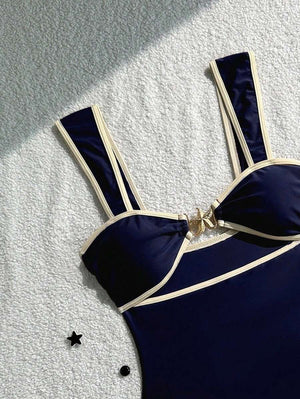 Detalle del corte y la silueta del traje de baño entero azul marino con ribetes en color crema.