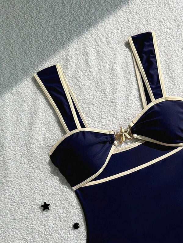 Detalle del corte y la silueta del traje de baño entero azul marino con ribetes en color crema.