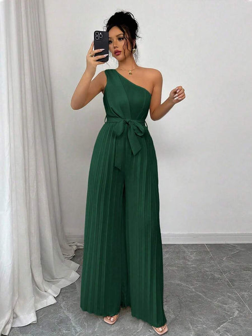 Mujer vistiendo un jumpsuit elegante verde oscuro de un solo hombro con piernas anchas plisadas.