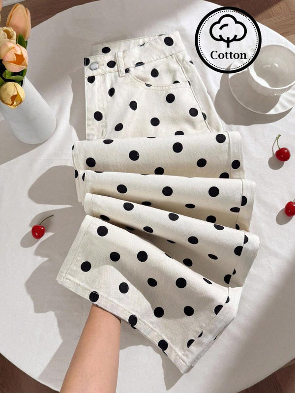 Pantalones de lona blancos con lunares negros doblados sobre una mesa blanca.