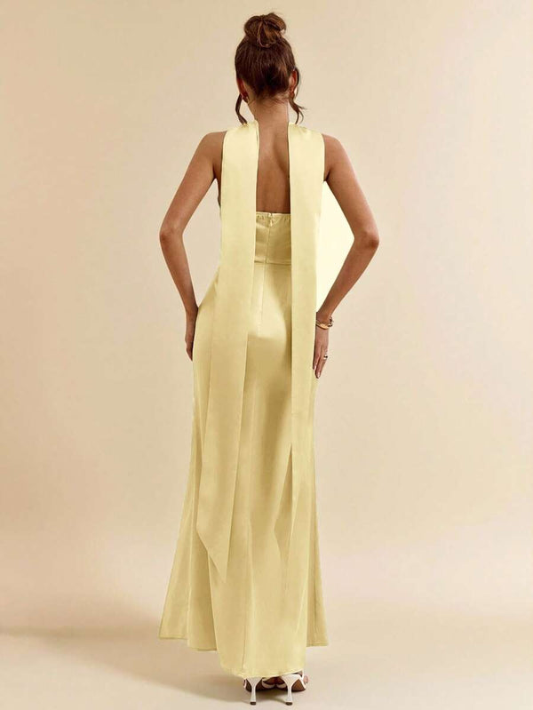 Detalle superior de un vestido amarillo strapless con drapeado y lazo al cuello.