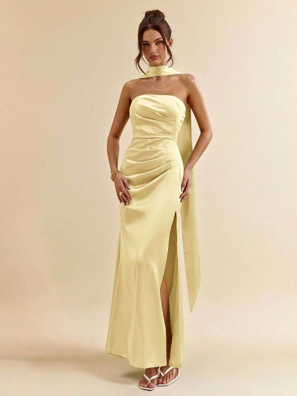 Parte inferior de un vestido largo amarillo con abertura en la pierna, combinado con sandalias blancas.