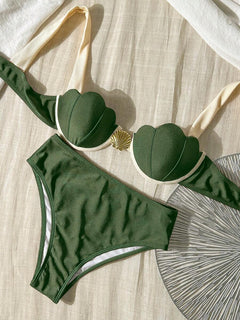 Detalle cercano del broche dorado en forma de concha en el centro de un top de bikini push up.