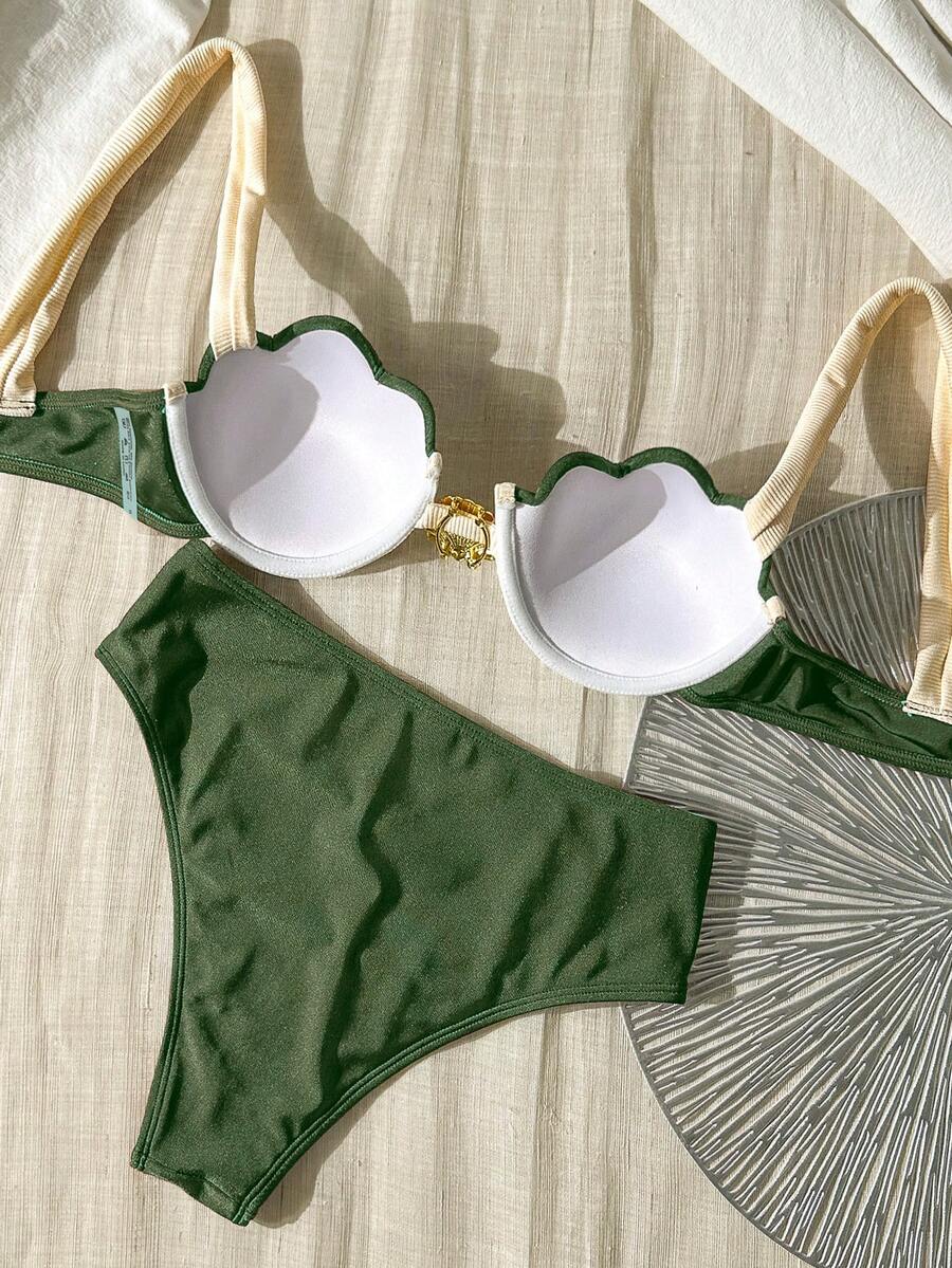 Detalle cercano del broche dorado en forma de concha en el centro de un top de bikini push up.