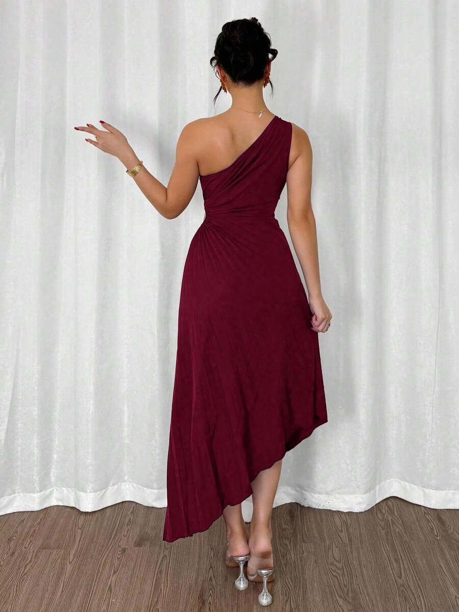 Vista completa de una mujer luciendo un vestido midi asimétrico color vino de un solo hombro con falda plisada.
