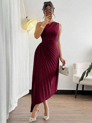 Primer plano de la falda plisada con corte asimétrico de un vestido midi color vino.
