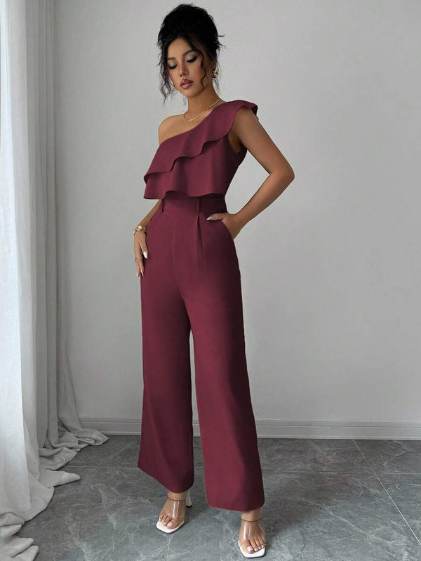 Vista frontal de mujer vistiendo un jumpsuit asimétrico color vino con cinturón.