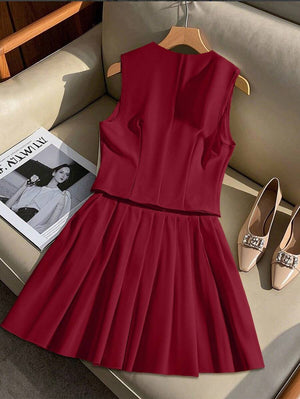 Conjunto completo de chaleco y falda plisada color vino exhibido en un sillón color crema.