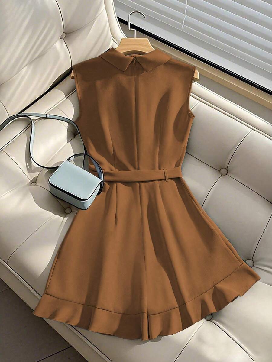 Romper elegante color café sin mangas con cuello de solapa y cinturón, visto desde arriba sobre un sofá.