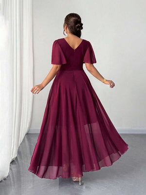 Primer plano del torso de una mujer con un vestido burdeos, destacando el escote cruzado y las mangas de gasa transparente.
