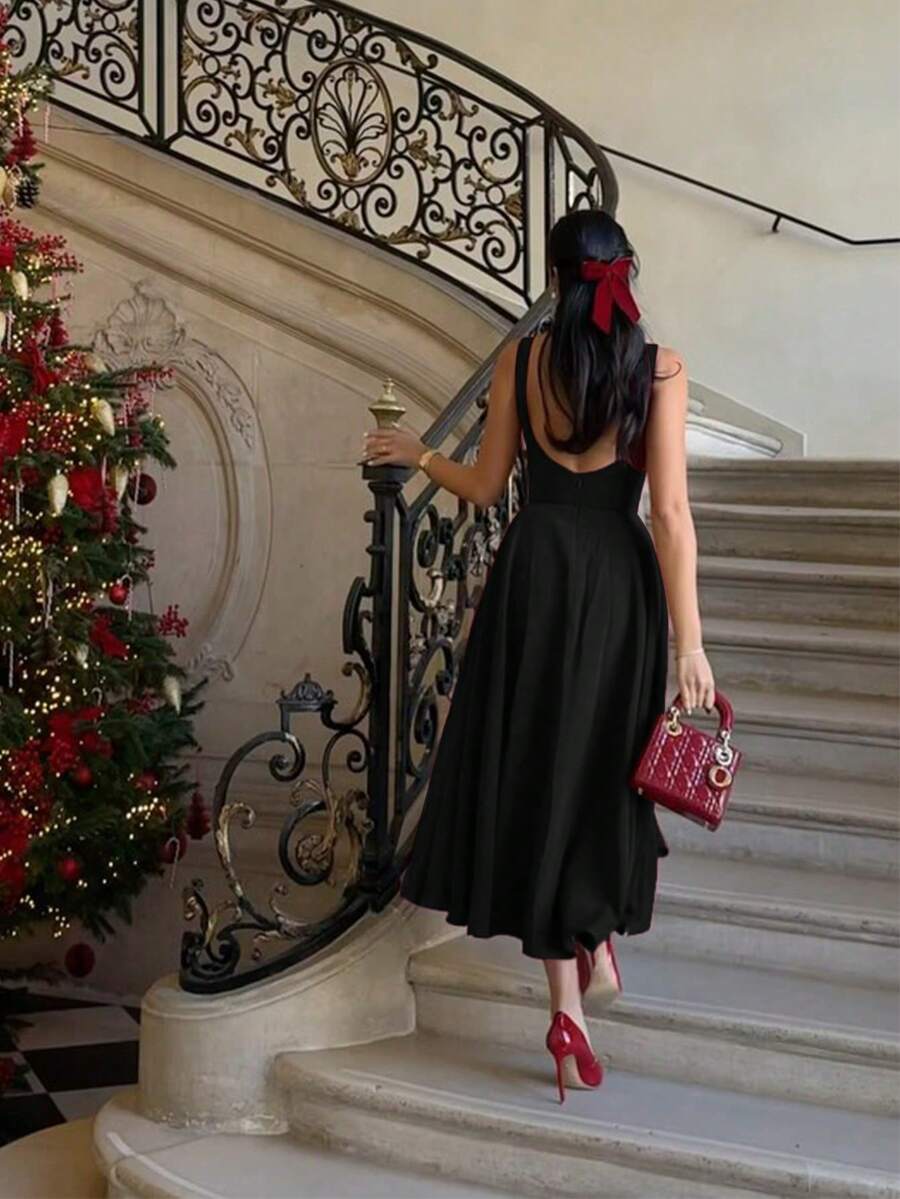 Vista completa de una mujer usando un vestido midi negro elegante sin mangas con falda amplia.