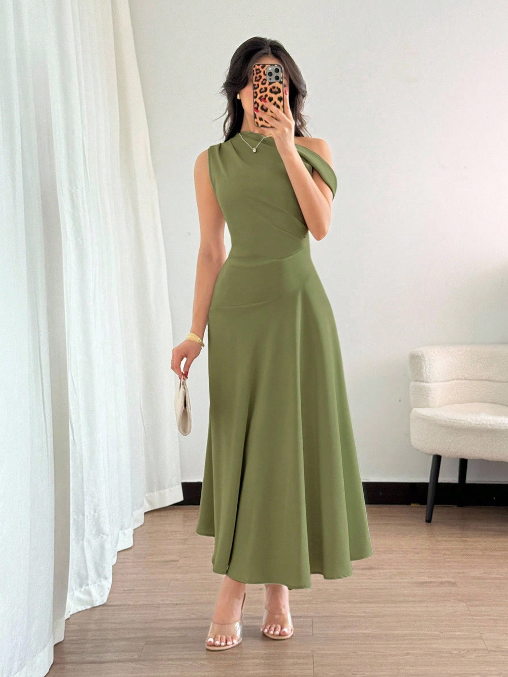 Vestido verde oliva elegante con cuello asimétrico y falda acampanada.