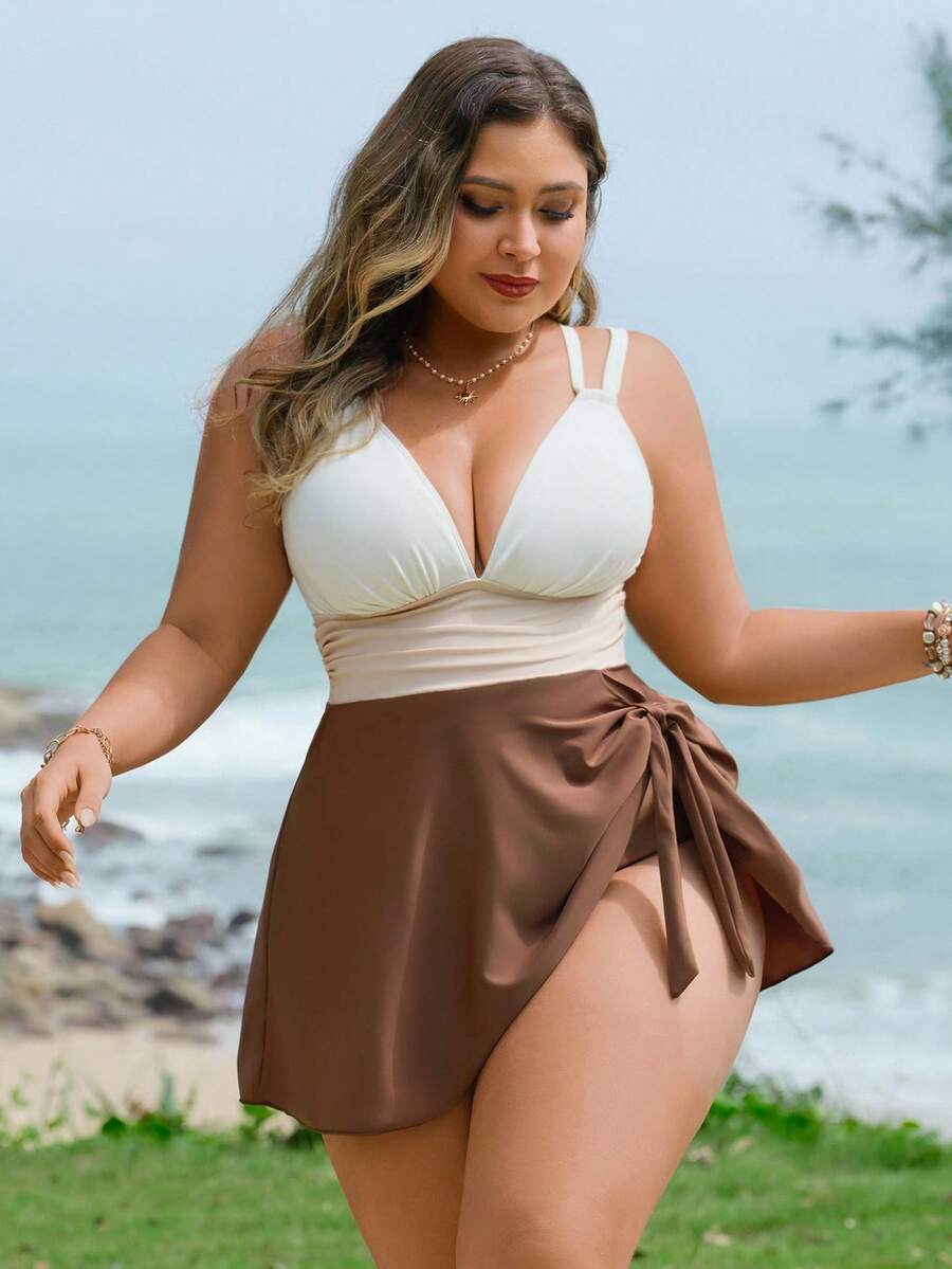 Mujer de talla grande posando en la playa con un traje de baño de una pieza tricolor con falda café y escote v.