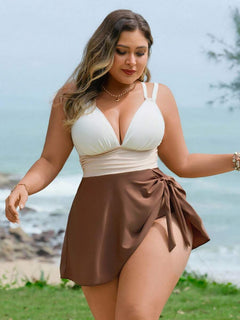 Mujer de talla grande posando en la playa con un traje de baño de una pieza tricolor con falda café y escote v.