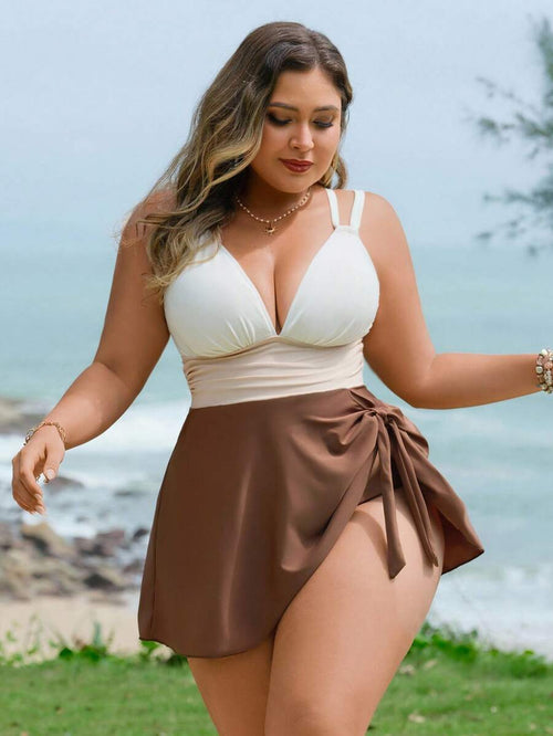 Mujer de talla grande posando en la playa con un traje de baño de una pieza tricolor con falda café y escote v.