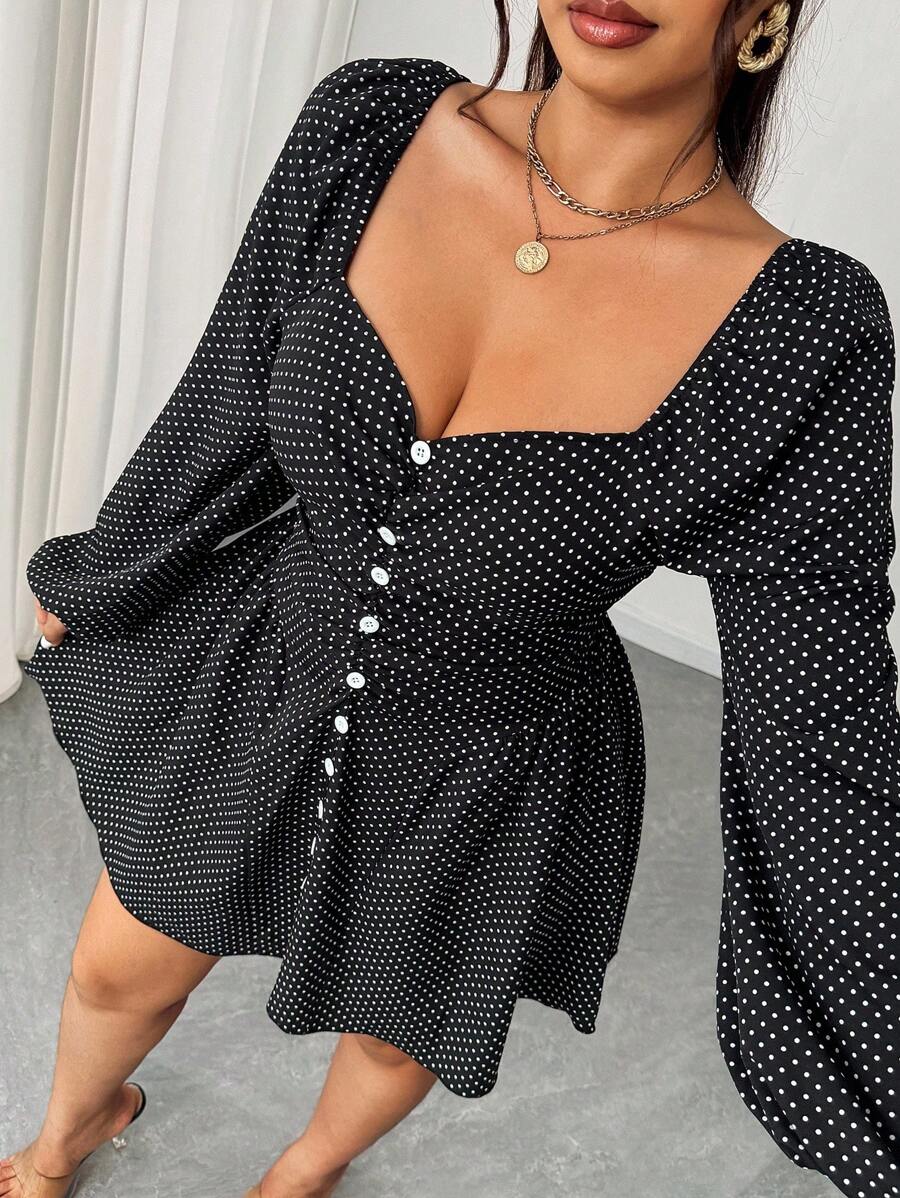 Mujer posando de frente con un vestido negro corto de lunares blancos, escote corazón y mangas largas abullonadas.