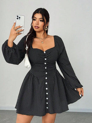 Mujer posando de frente con un vestido negro corto de lunares blancos, escote corazón y mangas largas abullonadas.