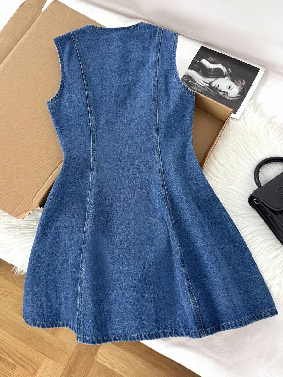 Vestido de mezclilla sin mangas con botones dorados frontales y corte en línea A sobre una superficie blanca.