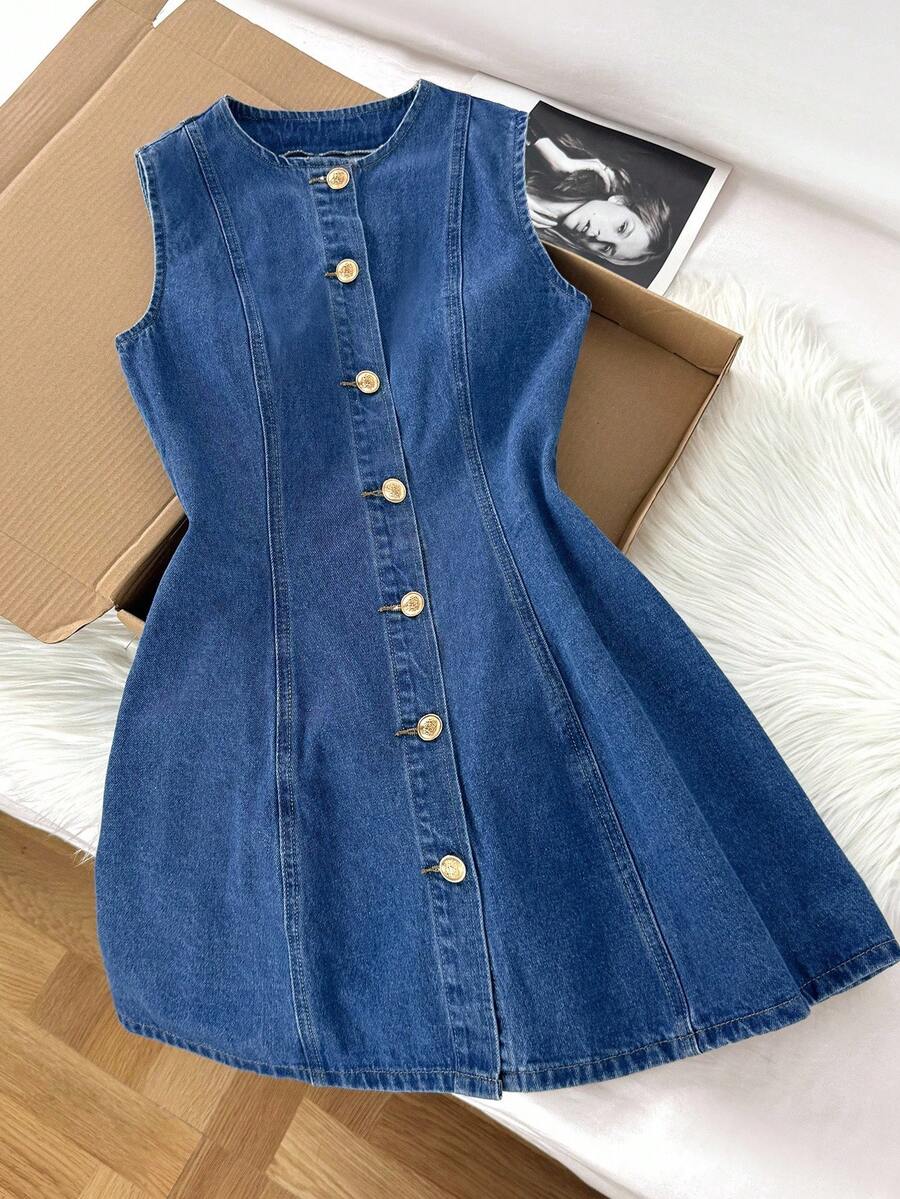 Vestido de mezclilla sin mangas con botones dorados frontales y corte en línea A sobre una superficie blanca.