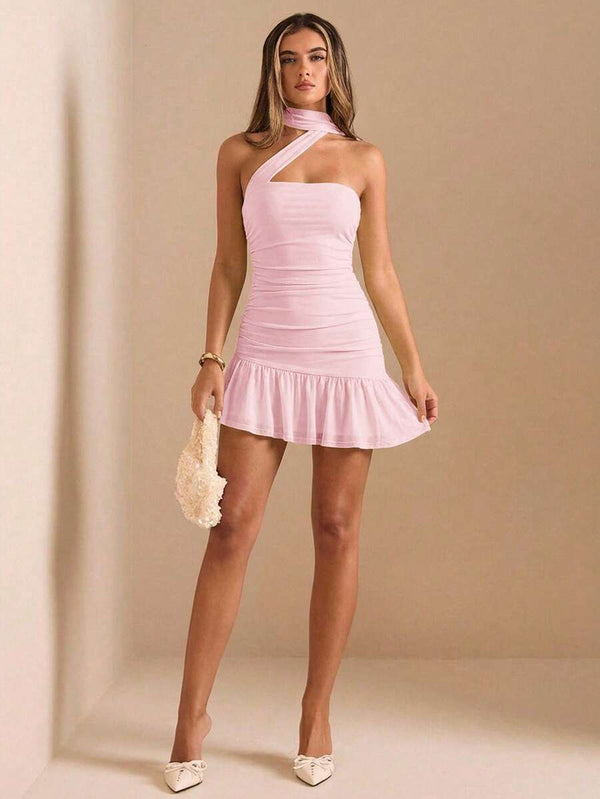 Detalle del bajo con volante de un mini vestido rosa y piernas de la modelo con tacones blancos.