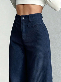 Vista frontal de un pantalón de pana ancho azul marino de talle alto en una modelo.
