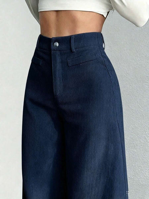 Vista frontal de un pantalón de pana ancho azul marino de talle alto en una modelo.