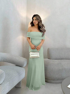 Mujer con vestido largo elegante color verde menta posando de pie en una sala moderna.
