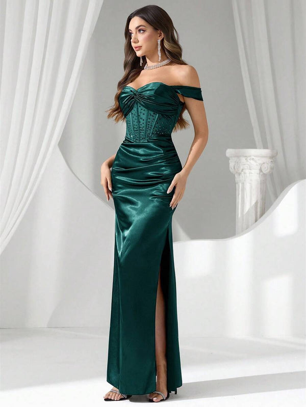 Detalle de la silueta de un vestido de fiesta satinado color verde con hombros caídos y drapeado en la cintura.
