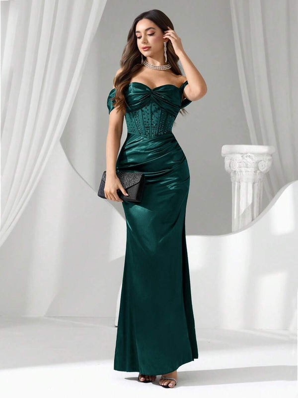 Parte inferior de un vestido de noche largo verde esmeralda mostrando la abertura lateral y el tejido satinado.