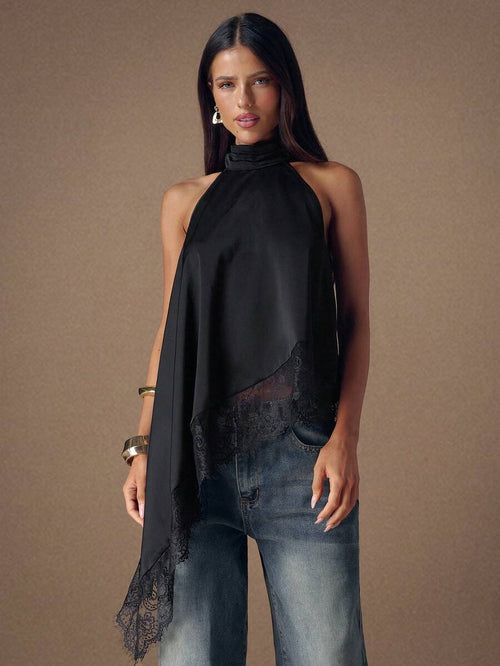 Vista frontal de una mujer usando una blusa halter asimétrica negra con encaje y jeans.