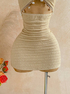 Detalle del top halter beige con textura y collares dorados en el maniquí.