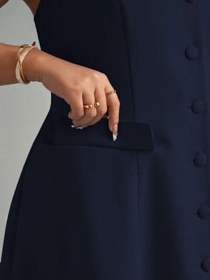 Detalle lateral de la falda con vuelo y el bolsillo con solapa de un vestido azul marino.