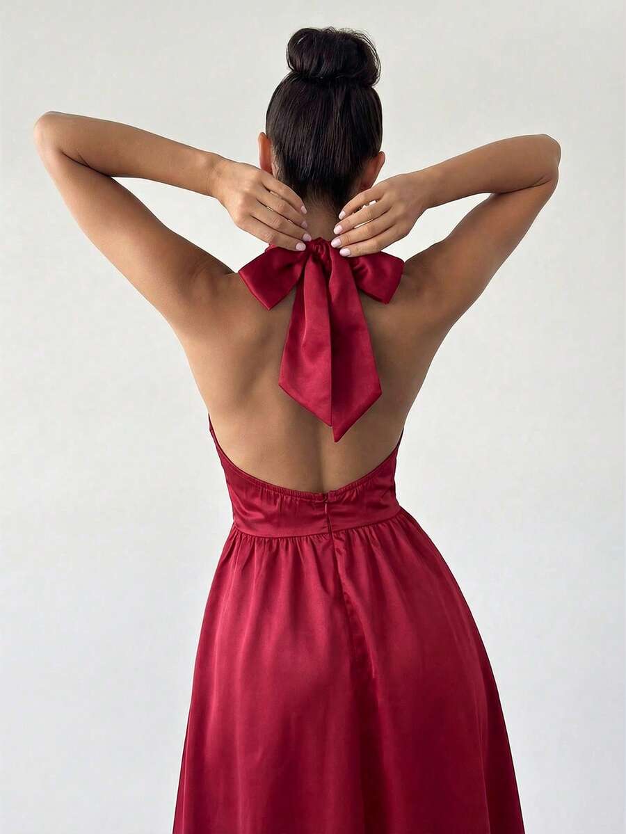Mujer elegante posando con un vestido rojo de satén con cuello halter y falda midi.