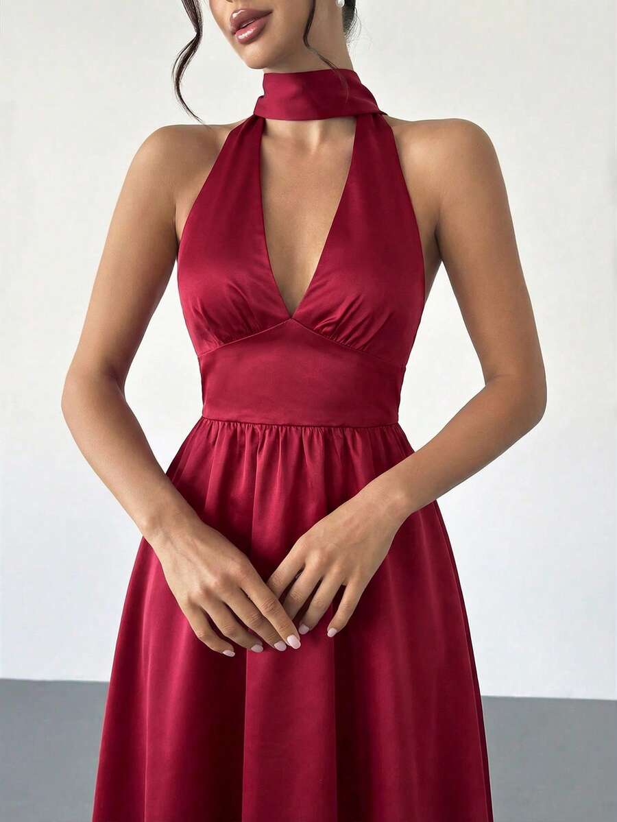 Mujer elegante posando con un vestido rojo de satén con cuello halter y falda midi.