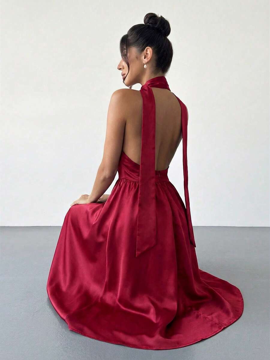 Mujer elegante posando con un vestido rojo de satén con cuello halter y falda midi.
