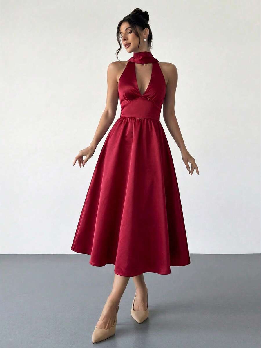 Mujer elegante posando con un vestido rojo de satén con cuello halter y falda midi.