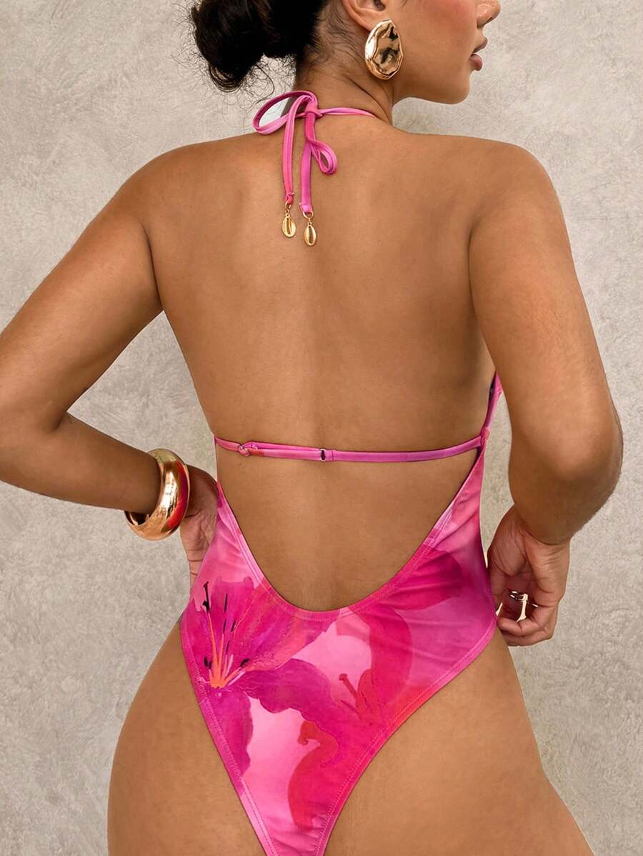 Mujer modelando traje de baño entero fucsia con estampado floral y escote halter.
