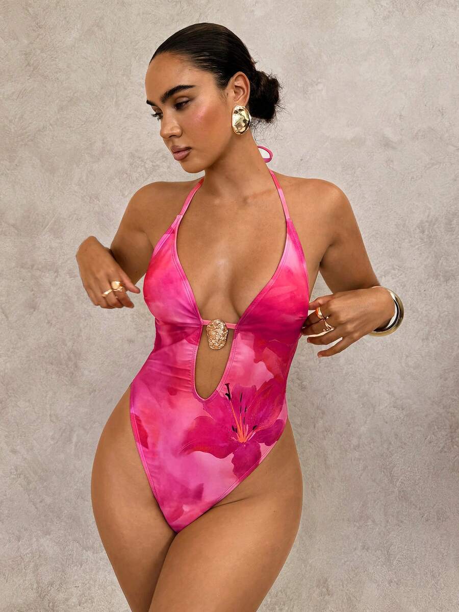 Mujer modelando traje de baño entero fucsia con estampado floral y escote halter.